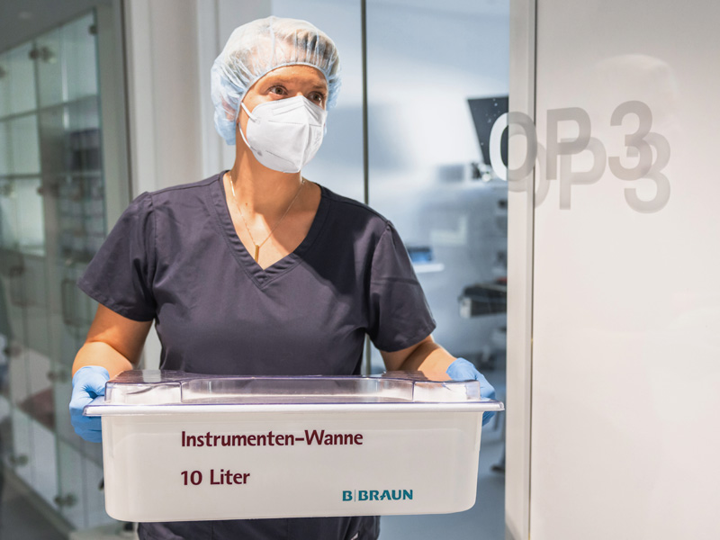 Klinisches Personal handhabt gereinigte chirurgische Instrumente auf einem Tablett im Rahmen der Instrumentenaufbereitung und -pflege in einer klinischen Umgebung.