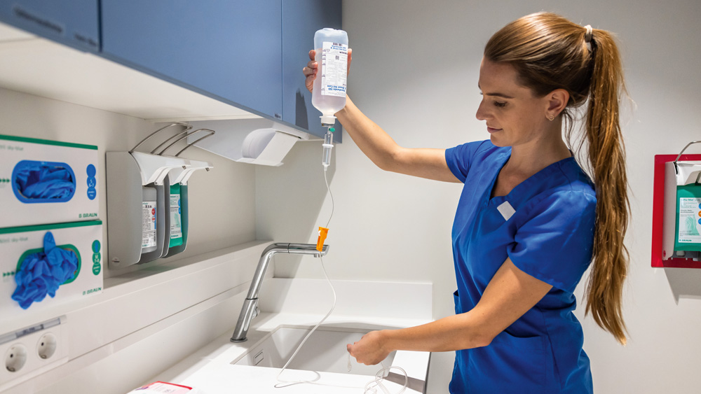 Eine tiermedizinische Fachangestellte bereitet ein Infusionssystem an einem klinischen Arbeitsplatz vor, der mit medizinischen Vorräten ausgestattet ist.