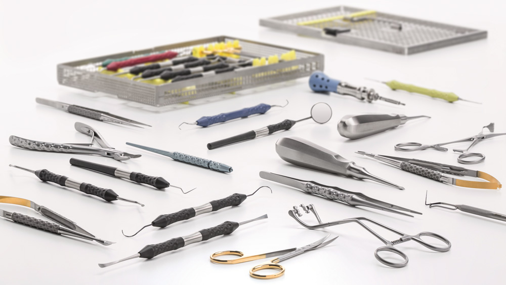 Sortiment aus dentalen Instrumenten und Werkzeugen, ausgelegt auf einer weißen Oberfläche neben einer geöffneten Aufbewahrungsschale.